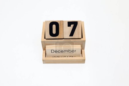 Close up of a wooden perpetual calendar showing the 7th of December. Shot close up isolated on a white background 