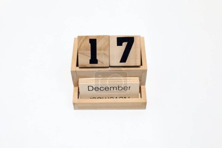 Primer plano de un calendario perpetuo de madera que muestra el 17 de diciembre. Disparo de cerca aislado sobre un fondo blanco 