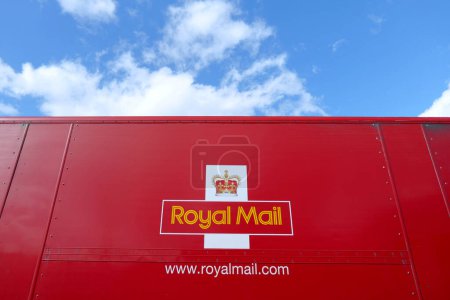 Photo for Carlisle UK 3 29 2024 Red Royal Mail lorry below blue sky with white clouds. Company crown logo set against iconic red on the lorry side - Royalty Free Image