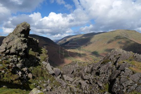 Rocky outcrop of the lion and lamb at the top of Helmcrag in the Lake District National Park. Cumbrian fells can be seen in the backdrop.