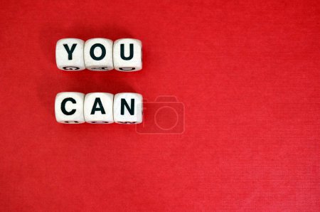 Photo for You Can spelt with wooden word dice above a red cardboard background. - Royalty Free Image