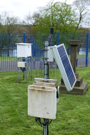 Weather recording equipment setup outside. A solar panel can be seen, and a whte stevenson screen is blurred in the background.