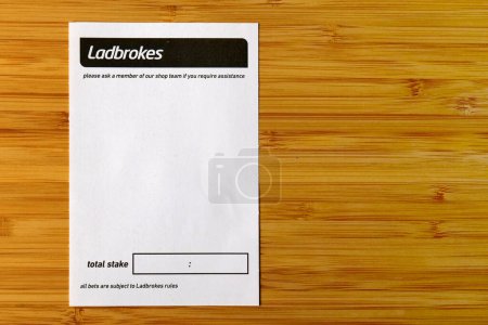 Foto de Bradford, Reino Unido 05 04 2024 Ladbrokes en blanco sobre un fondo de madera pálido con espacio para copiar a la derecha - Imagen libre de derechos