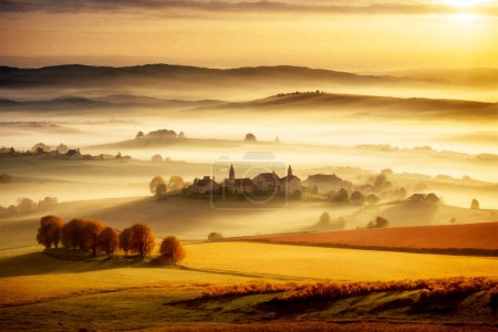 Téléchargez les photos : Paysage rural européen automnal serein avec des champs d'arbres de collines et village lointain. Parfait pour la vente d'automne. - en image libre de droit