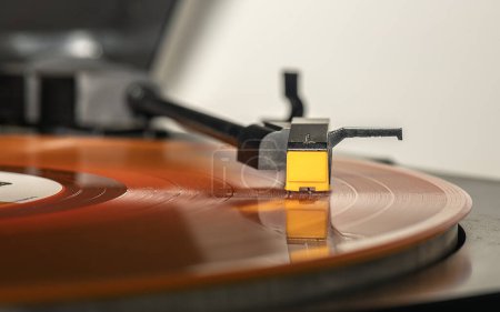 Foto de Hace un sonido de melodía mientras se cierne sobre la aguja de un tocadiscos naranja de larga duración. - Imagen libre de derechos
