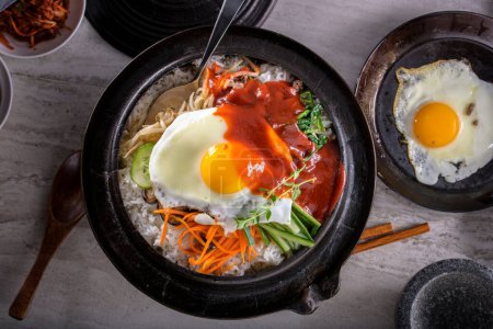 Sizzling Bi Bim Bap : 4K Ultra HD Top View, légumes mélangés, riz et sauce piquante dans un pot en fonte