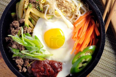 Sizzling Bi Bim Bap : 4K Ultra HD Top View, légumes mélangés, riz et sauce piquante dans un pot en fonte