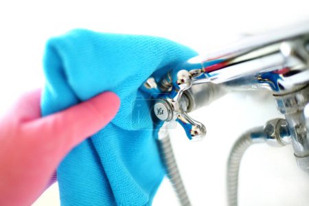 Routine Bathroom Cleaning: Closeup of Unrecognizable Person's Hand in Pink Glove Cleaning Bathtub Faucet with Blue Cloth (4K Image)