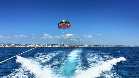 Thrilling Parasailing Adventure: Two People Soaring Over Sea on Summer Vacation Behind Speedboat (4K image)