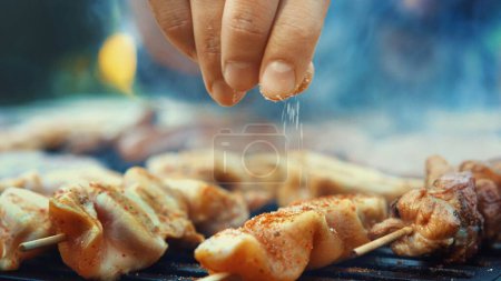 Sizzling BBQ: Closeup of Unrecognizable Person Flipping Meat and Sausages on Grill, Ready for Serving, Slowly Panning Upwards (4K image)