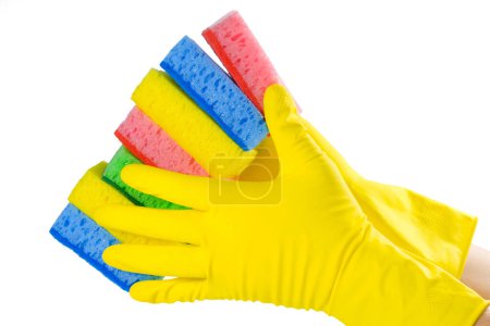 Una mano en un guante amarillo sostiene un conjunto de esponjas aisladas sobre un fondo blanco. Primer plano.