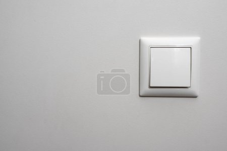 Photo for White light switch, a plastic mechanical switch of white color installed on a light gray wall. - Royalty Free Image