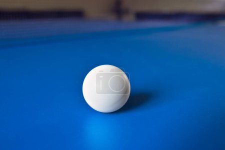Foto de Una pelota de tenis blanca sobre una mesa azul con el reflejo. Ping Pong, juegos de mesa. - Imagen libre de derechos