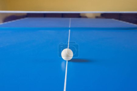 Foto de Una pelota para tenis de mesa en la mesa azul con una red. Deportes. - Imagen libre de derechos