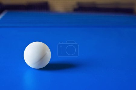 Foto de Pelota de tenis de mesa blanca sobre mesa azul. Pelota para jugar ping pong. Concepto deportivo. - Imagen libre de derechos