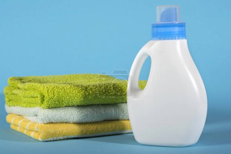 Foto de Botella con detergente y toallas sobre fondo azul. - Imagen libre de derechos