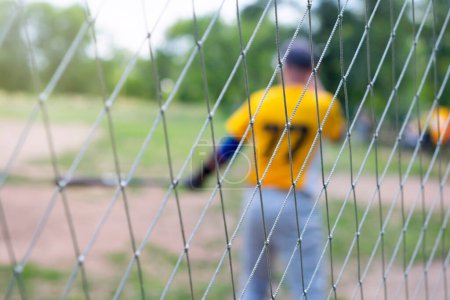 Foto de Jugador de béisbol en desenfoque en el campo, sobre una cerca de malla de alambre. - Imagen libre de derechos