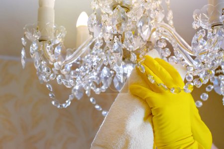 Photo for Hands in gloves clean the chandelier with a rag. Close-up. House cleaning. - Royalty Free Image