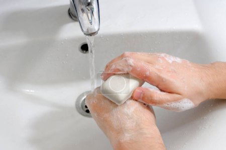 Manos debajo del grifo con agua sobre el lavabo en el baño. Concepto de higiene.