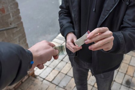 Photo for An addict with money buys a dose from a dealer on the street. Addiction concept. - Royalty Free Image