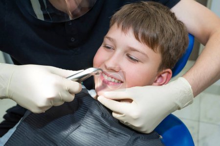 Téléchargez les photos : Portrait d'enfant patient et mains d'enfant dentiste avec pinces dentaires, gros plan. - en image libre de droit