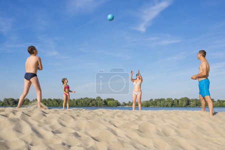Téléchargez les photos : Les enfants et leurs parents jouent au volley-ball sur la rive par une journée ensoleillée d'été. - en image libre de droit