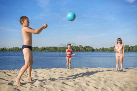 Téléchargez les photos : Enfants avec mère jouant avec une balle de volley-ball sur la rive. - en image libre de droit
