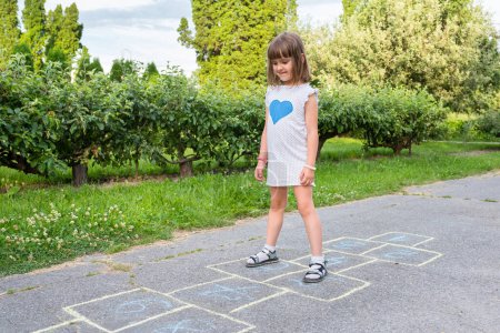 Photo for Smiling girl in the park, playing on the pavement. Child outdoors. - Royalty Free Image