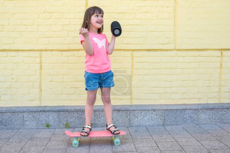 Téléchargez les photos : Bonne fille de la ville avec un skateboard amusez-vous en plein air. Mode de vie actif. - en image libre de droit