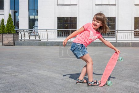 Téléchargez les photos : Petite fille apprend à skater par une journée ensoleillée en plein air. Mode de vie. - en image libre de droit