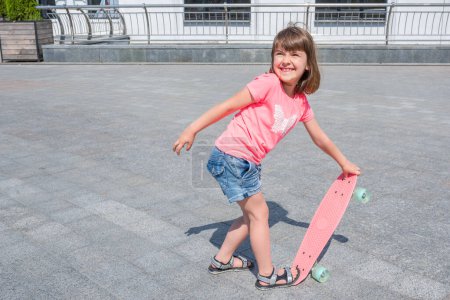 Téléchargez les photos : Petite fille apprend à skater par une journée ensoleillée en plein air. Mode de vie. - en image libre de droit