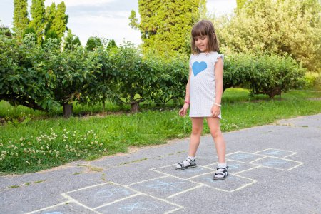 Photo for Cute child on the pavement draws and plays children's games. - Royalty Free Image
