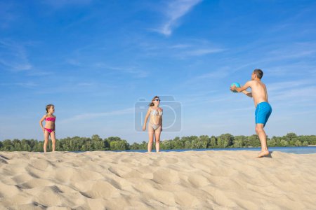Téléchargez les photos : Famille sur la rive de la rivière jouant au beach-volley par une journée ensoleillée d'été. - en image libre de droit
