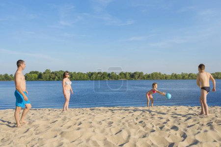 Téléchargez les photos : Bonne famille à la plage jouant avec un ballon. Mode de vie sain. - en image libre de droit