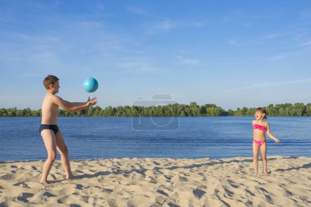 Téléchargez les photos : Les enfants heureux sur la plage jouent avec une balle. Vacances d'été. Mode de vie. - en image libre de droit