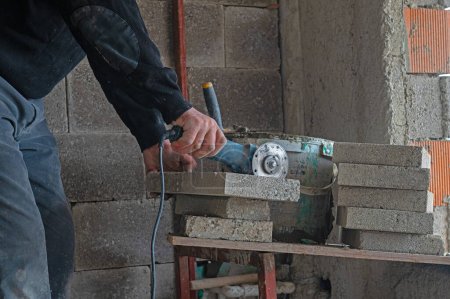 Téléchargez les photos : Le contremaître de chantier coupe la briquette avec un outil de coupe. - en image libre de droit