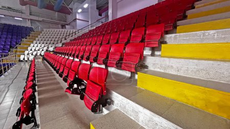 Téléchargez les photos : Sièges de spectateurs colorés dans la salle de sport intérieure. - en image libre de droit