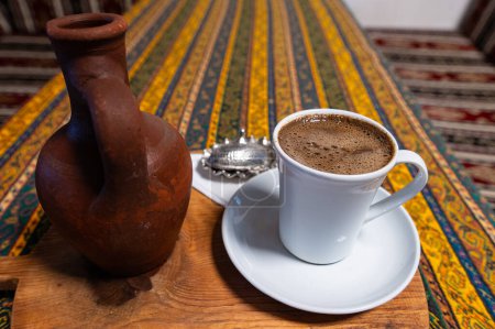 Téléchargez les photos : Café turc au cumin noir dans une tasse, une porte d'eau et une assiette de délices turcs sur la table. - en image libre de droit