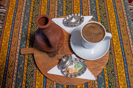 Téléchargez les photos : Café turc au cumin noir dans une tasse, une porte d'eau et une assiette de délices turcs sur la table. - en image libre de droit