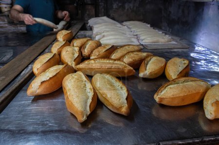 Photo for The baker putting the bread dough into the oven. Turkish bread production process. - Royalty Free Image