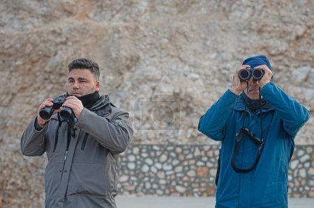 Two men bird-watching with binoculars.