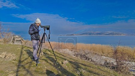 Un hombre observando aves con un telescopio en el lago. Lago Egirdir en Turquía.