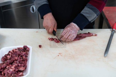 The butcher cuts the meat into small pieces.
