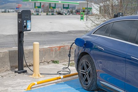 The power supply plugged into an electric car to charging a battery at the charging station.