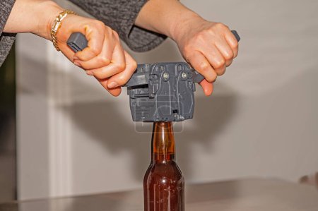 Woman using a cap to attach metal lids to beer bottles.