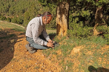 Ein Mann, der eine Fotofalle in einen Baum stellte, um wilde Tiere zu filmen.