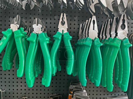 Various pliers in green on the shop shelf.