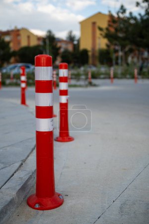 Cono de tráfico naranja, aparcamiento está prohibido. Barrera roja de plástico. Fila de poste de barrera de tráfico rojo y blanco en la carretera. Una barrera hecha de columnas de plástico con pigmento reflectante en una carretera asfaltada. Concepto de peligro.