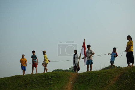 Téléchargez les photos : Un groupe d'enfants qui tirent de la guerre. Cette tradition est souvent réalisée comme un concours pour commémorer la fête de l'indépendance indonésienne le 17 août tangerang, 06 août 2023. - en image libre de droit