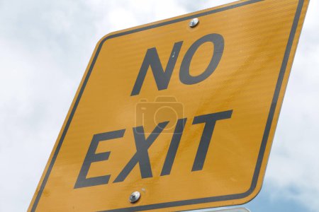 Photo for No exit square street sign with black writing and border in capital letter on yellow background with sky behind it shot on angle - Royalty Free Image